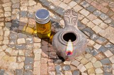 an old vase with a candle in it sitting on the ground next to a bottle