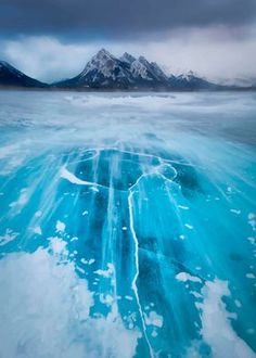 an ice floet in the water with mountains in the background and clouds overhead