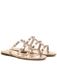 Embrace the fuss-free sandal silhouette of the season with Valentino Garavani's Italian-made Rockstud leather sandals. Presented in glamorous golden leather, this flat style works a caged design that is uplifted by metallic pyramid stud embellishments. Let yours ground bold color palettes and monochrome ensembles alike. Valentino Sandals, Valentino Garavani Shoes, Shearling Slippers, Ancient Greek Sandals, Valentino Rockstud, Valentino Shoes, Greek Sandals, Slides Sandals, Jelly Sandals