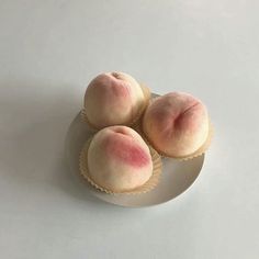 three peaches sitting on top of a white plate