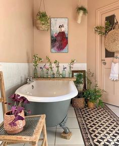 a bath tub sitting next to a table with flowers on it and potted plants