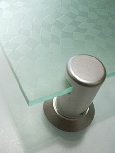 a glass table top with a metal base and silver knobs on it's end