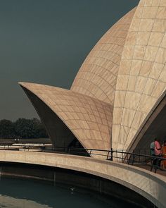 two people sitting on a bench in front of the sydney opera house, looking out over the water