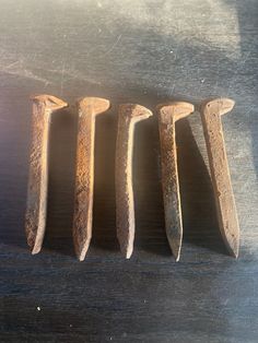 five old rusty nails sitting on top of a wooden table