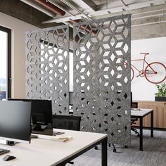 an office cubicle with two computers and a bike in the background