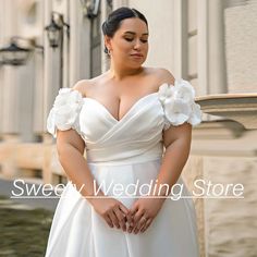 a woman in a white wedding dress posing for the camera with her hands on her hips