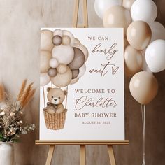 a welcome sign with balloons and a teddy bear in a hot air balloon basket on an easel