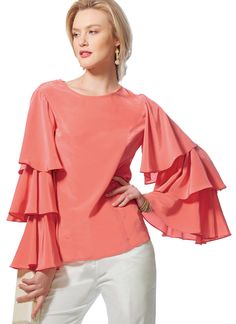 a woman is wearing an orange top with ruffles on the sleeves and shoulders