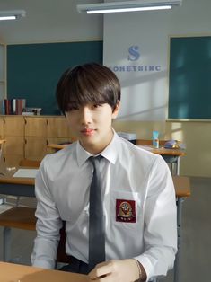 a young man wearing a white shirt and tie sitting at a desk in an office