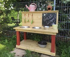 an outdoor kitchen made out of pallets and wooden planks with metal bowls on it