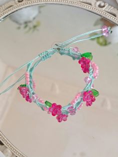 a close up of a mirror with some beads and flowers on the string attached to it