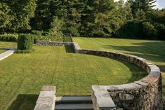 a large grassy area with steps leading up to the grass covered lawn and trees in the background