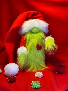 a green stuffed animal wearing a santa hat on top of a red cloth covered table