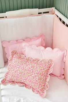 pink and green pillows in a white crib