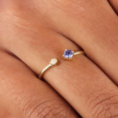 a woman's hand with a ring on it and a blue stone in the middle