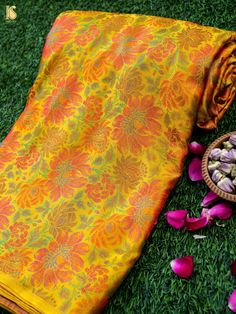 an orange and yellow sari laying on the ground next to some pink flower petals