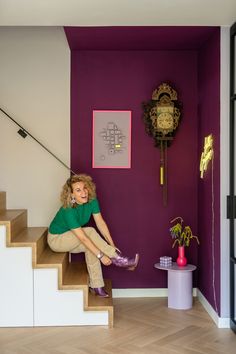 a woman is sitting on the stairs in her home