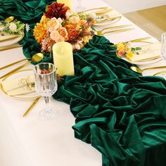 the table is set with green cloths and gold place settings, candles and flowers