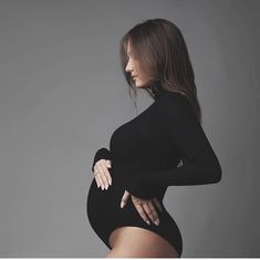 a woman in a black bodysuit posing for the camera with her hands on her hips