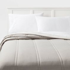 an unmade bed with white sheets and pillows