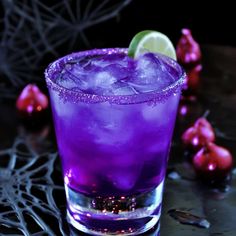 a purple drink sitting on top of a table next to pomegranates