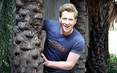 a man standing next to a tall palm tree