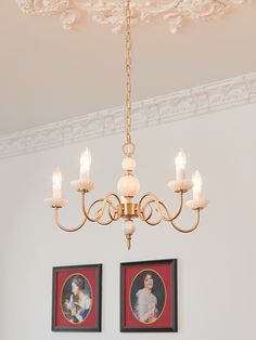 a chandelier hanging from the ceiling in a room with pictures on the wall