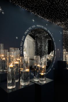 there are many glasses on the table with candles in front of them and stars hanging from the ceiling