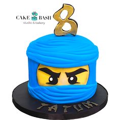 a cake that is shaped to look like a lego ninja's head with the number 8 on it