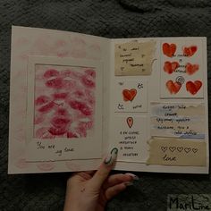 someone is holding an open book with pictures and hearts drawn on it, while the pages are lined up