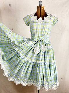 An authentic vintage patio or square dancing dress by Pom Pom Fashions label. a classic swing dress with a gathered and tiered full circle skirt. lace and ric rac trim. woven fabric. included matching sash tie belt. elastic waistband for comfort! era : 1950s material : cotton color : sky blue, lime condition : great, appropriate signs of age and wear as seen in photos size : approx xsmall to small , please compare measurements below shown on form with 36 chest - 26 waist actual garment measurements : chest : 36" shoulder : 15" arm : 12" around  waist : up to 30" skirt length: 26" total length : 41" - - - - - - - - - - - - - - - - - - - - - - - - - - - - - - - - - - - - - - - -  INTERNATIONAL SHIPPING AVAILABLE UPON REQUEST Craft Union does NOT accept returns or exchanges, all items are FIN Square Dancing Dresses, Vintage Tiered Dress With Lace Trim, Vintage Tiered Lace Trim Dresses, Vintage Terrarium, 1950s Western, Square Dance Dress, Pom Pom Fashion, Square Dance Dresses, Vintage Patio