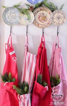 three red bags hanging on a wall with christmas decorations and plates in the back ground