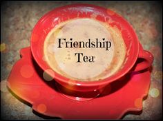 a red cup filled with liquid sitting on top of a saucer that says, friendship tea