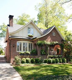 a brick house with white trim and lots of greenery on the front door is shown