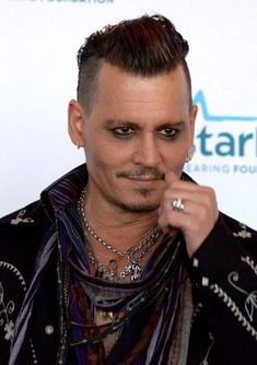 a man with black hair and piercings on his nose is posing for the camera