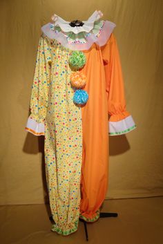 an orange and white clown costume on display in front of a brown backdrop with polka dots