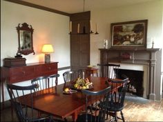 a dining room table and chairs with fruit on the plate in front of it next to a fireplace