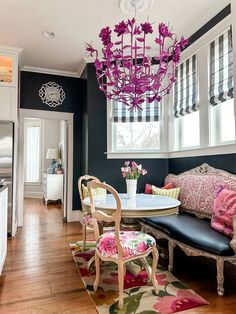 a living room with black walls and pink flowers on the chandelier above the table