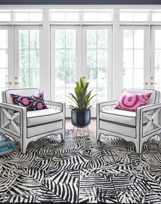 two white chairs sitting next to each other on top of a black and white rug