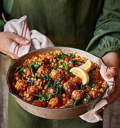 a person holding a pan filled with meat and vegetables