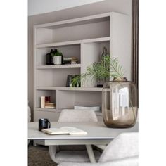 a white table with a vase and books on it in front of a book shelf