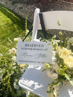 a white chair with flowers on it and a sign that says reserved in loving memory