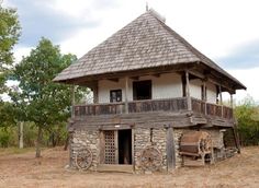 an old wooden building with a roof made out of logs and stone, sitting in the middle of a field