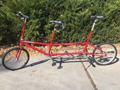 a red bicycle is parked in front of some bushes