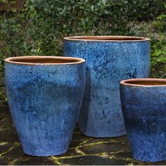 three blue pots sitting on top of a stone slab