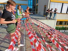 a group of young children standing next to each other on top of a walkway covered in red and white striped ribbon