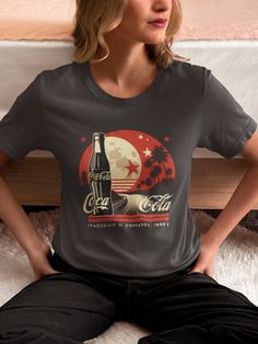 Vintage Coca Cola Graphic T-shirt The unisex soft-style t-shirt puts a new spin on casual comfort. Made from very soft materials, this tee is 100% cotton for solid colors. Heather colors and sports grey include polyester. The shoulders have twill tape for improved durability. There are no side seams. The collar is made with ribbed knitting to prevent curling damage.  .: Made with 100% ring-spun cotton, a lightweight fabric (4.5 oz/yd² (153 g/m this unisex t-shirt feels like a bliss to wear all year round.  .: The classic fit with the crew neckline deliver a clean, versatile style that can match any occasion, whether it's formal or semi-formal.  .: All shirts feature a pearlized, tear-away label for total wearing comfort.  .: Made using ethically grown and harvested US cotton. Gildan is als Retro Gray T-shirt For Streetwear, Vintage Gray Summer T-shirt, Retro Gray Graphic Print Top, Retro Gray Top With Graphic Print, Retro Gray Crew Neck Top, Retro Gray Short Sleeve Top, Gray Retro Crew Neck Top, Pop Culture Crew Neck T-shirt With Sublimation Print, Vintage Gray T-shirt With Text Print