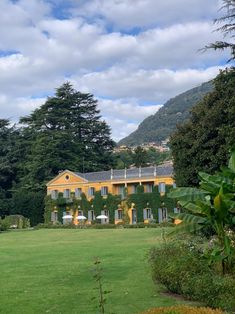 a large yellow house sitting in the middle of a lush green field next to trees