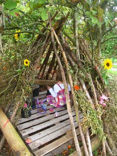 a child is sitting on a wooden platform in the woods with sunflowers and branches