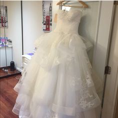 a wedding dress hanging on a hanger in front of a door with a mirror behind it